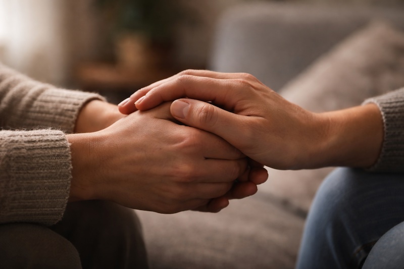 Deux mains se tenant doucement dans une lumière douce, symbolisant le soutien silencieux et la présence après l’annonce d’un diagnostic de sclérose en plaques.