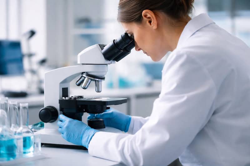 recherche-medicale-sclerose-en-plaques-laboratoire-scientifique Scientifique travaillant dans un laboratoire et observant un échantillon au microscope, illustrant la recherche médicale continue sur la sclérose en plaques.